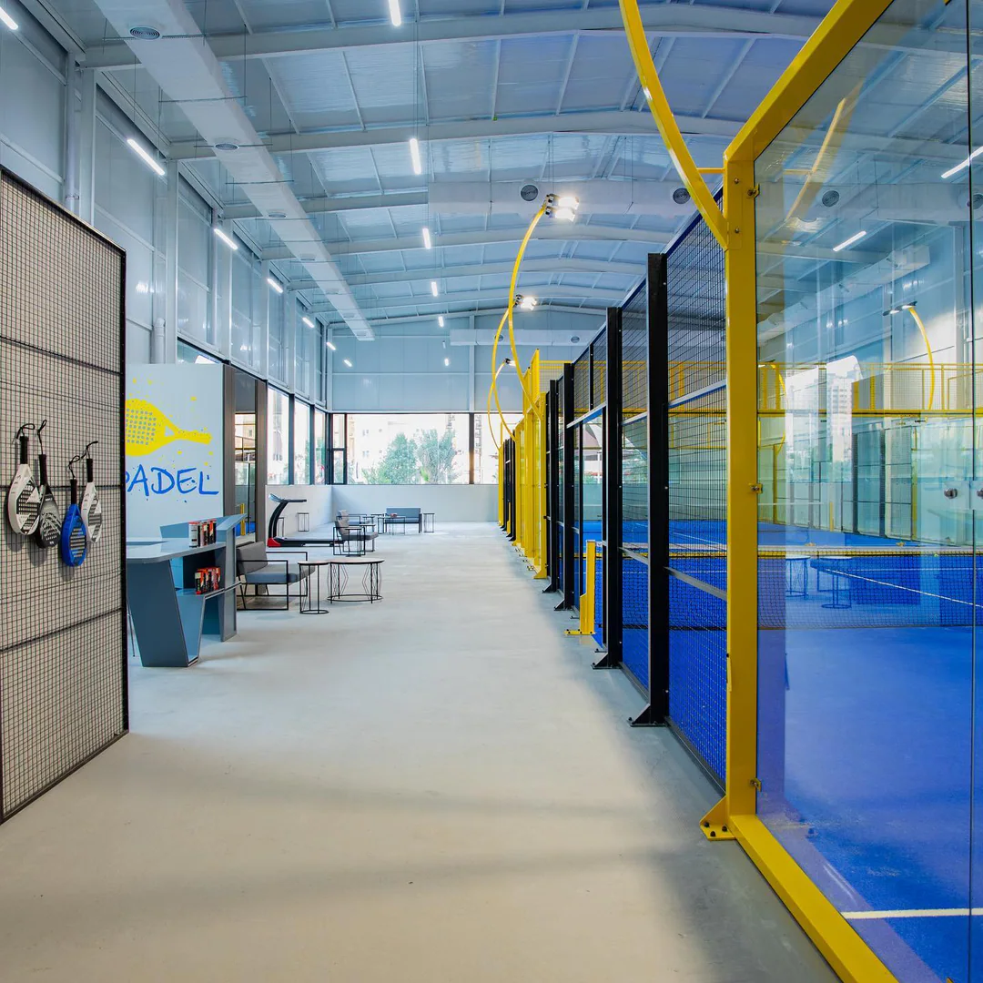 The walkway between the lounge and the courts, yellow frames and the PADEL wall