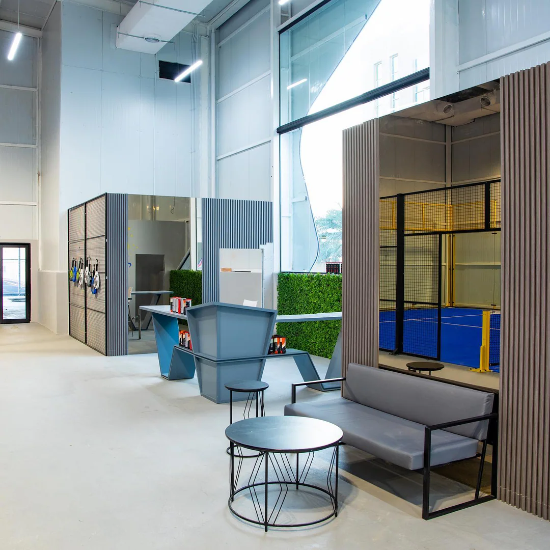 The lounge: grey sofas, green wall and a court behind glass
