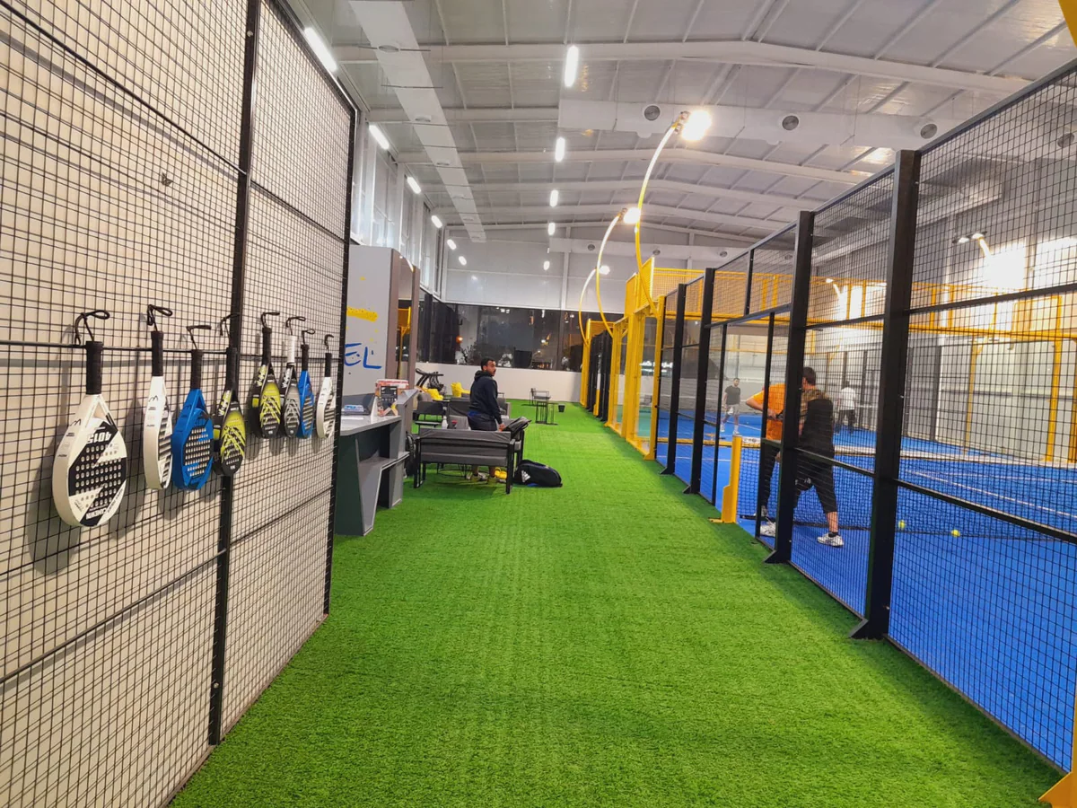Rackets hanging on the mesh wall beside the turf walkway
