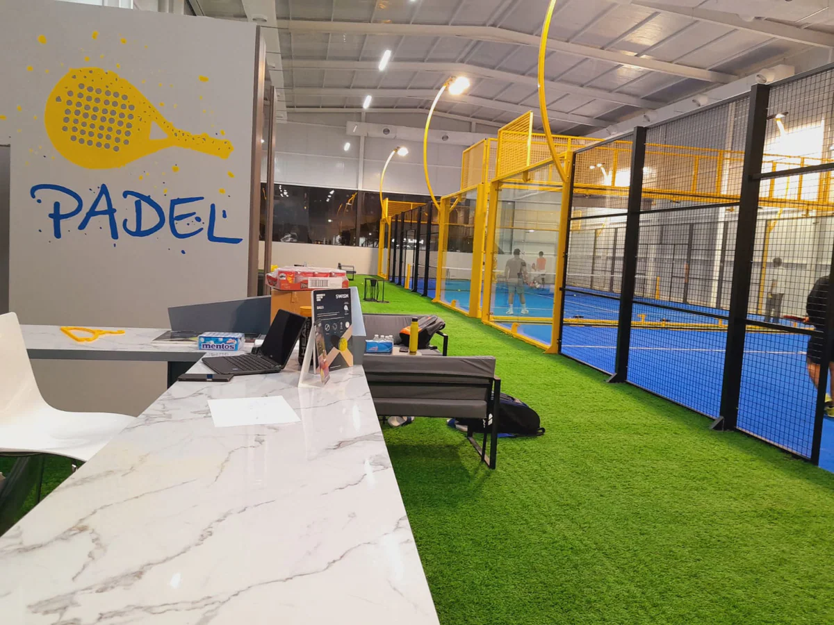 Reception desk with the painted PADEL wall, courts behind